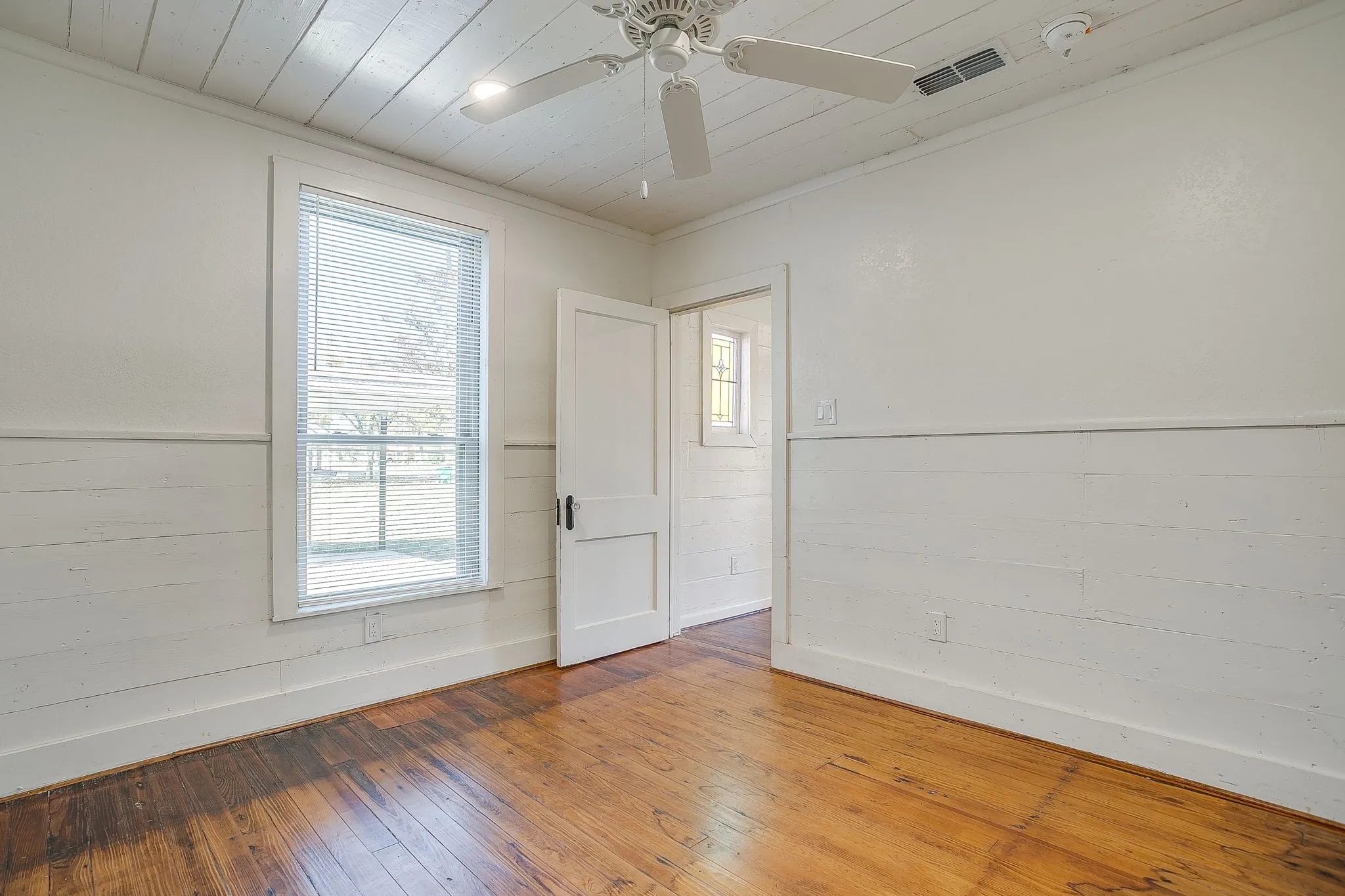 Unfurnished room with wainscoting, wooden ceiling, hardwood / wood-style flooring, plenty of natural light, and crown molding