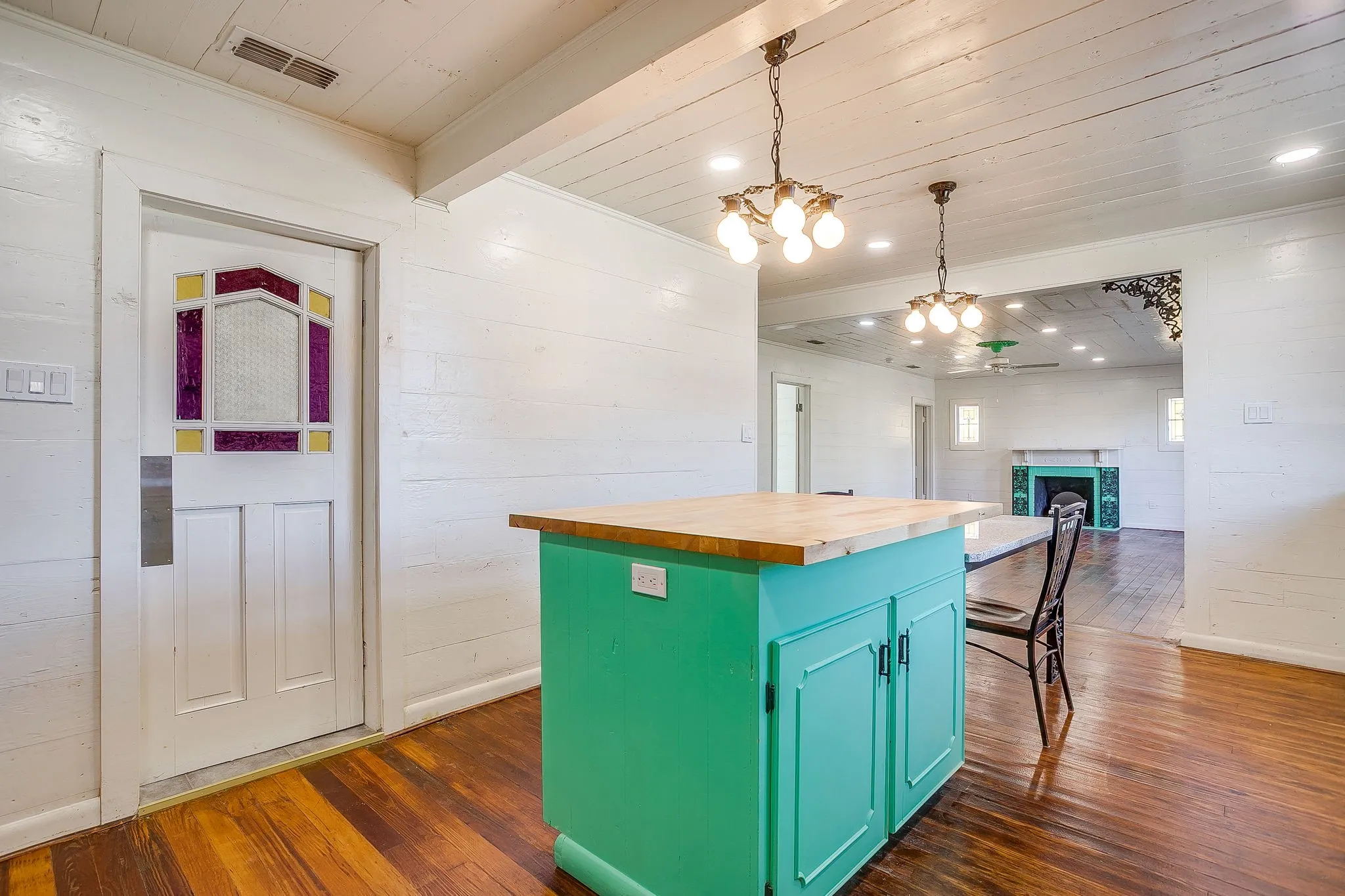 Kitchen with butcher block counters, decorative light fixtures, green cabinets, a wood ceiling with exposed beams, and a fireplace