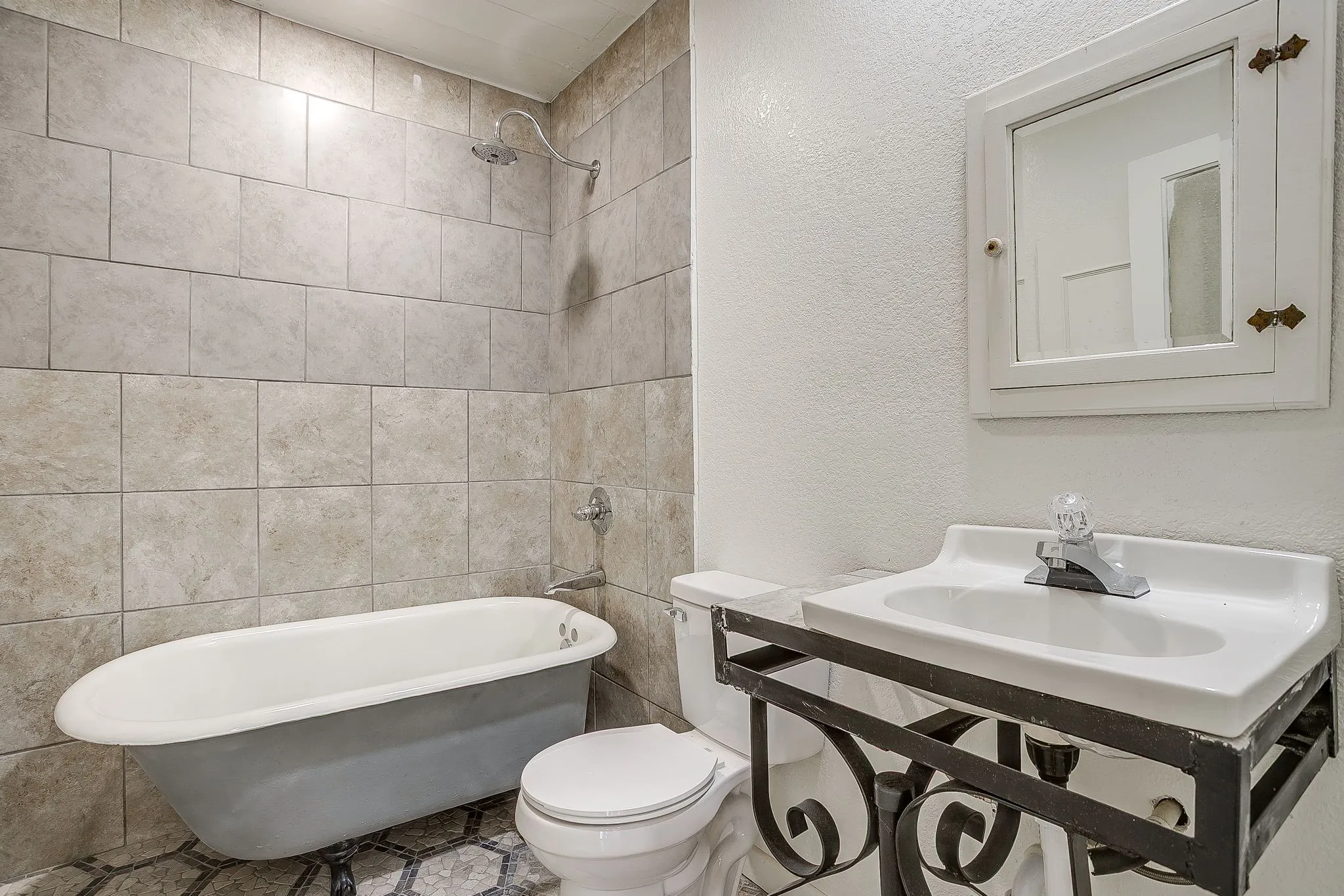Full bathroom with a textured wall, vanity, and bathing tub / shower combination