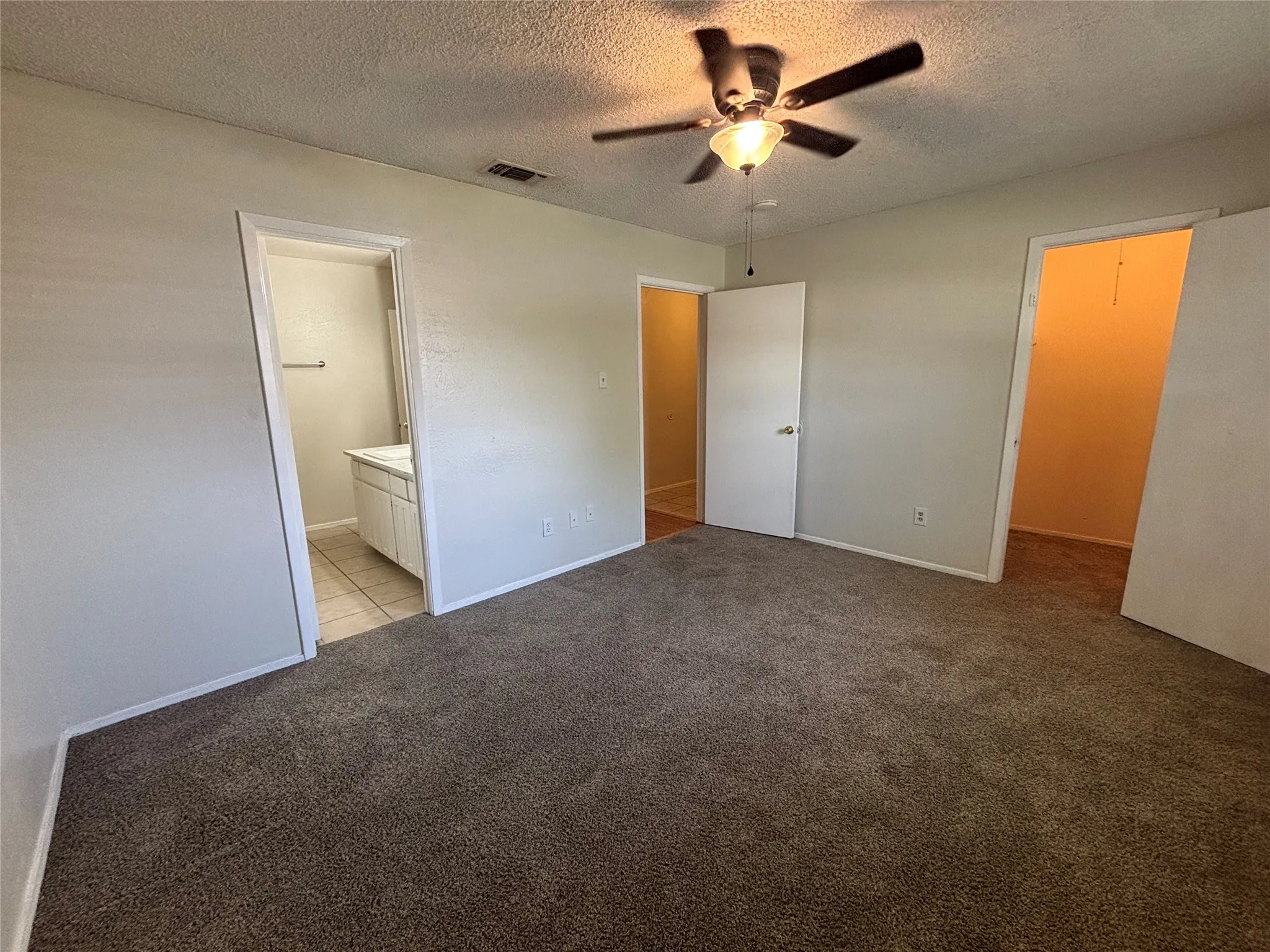 Spacious room featuring neutral-toned walls, brown carpeting, and a ceiling fan with integrated lighting