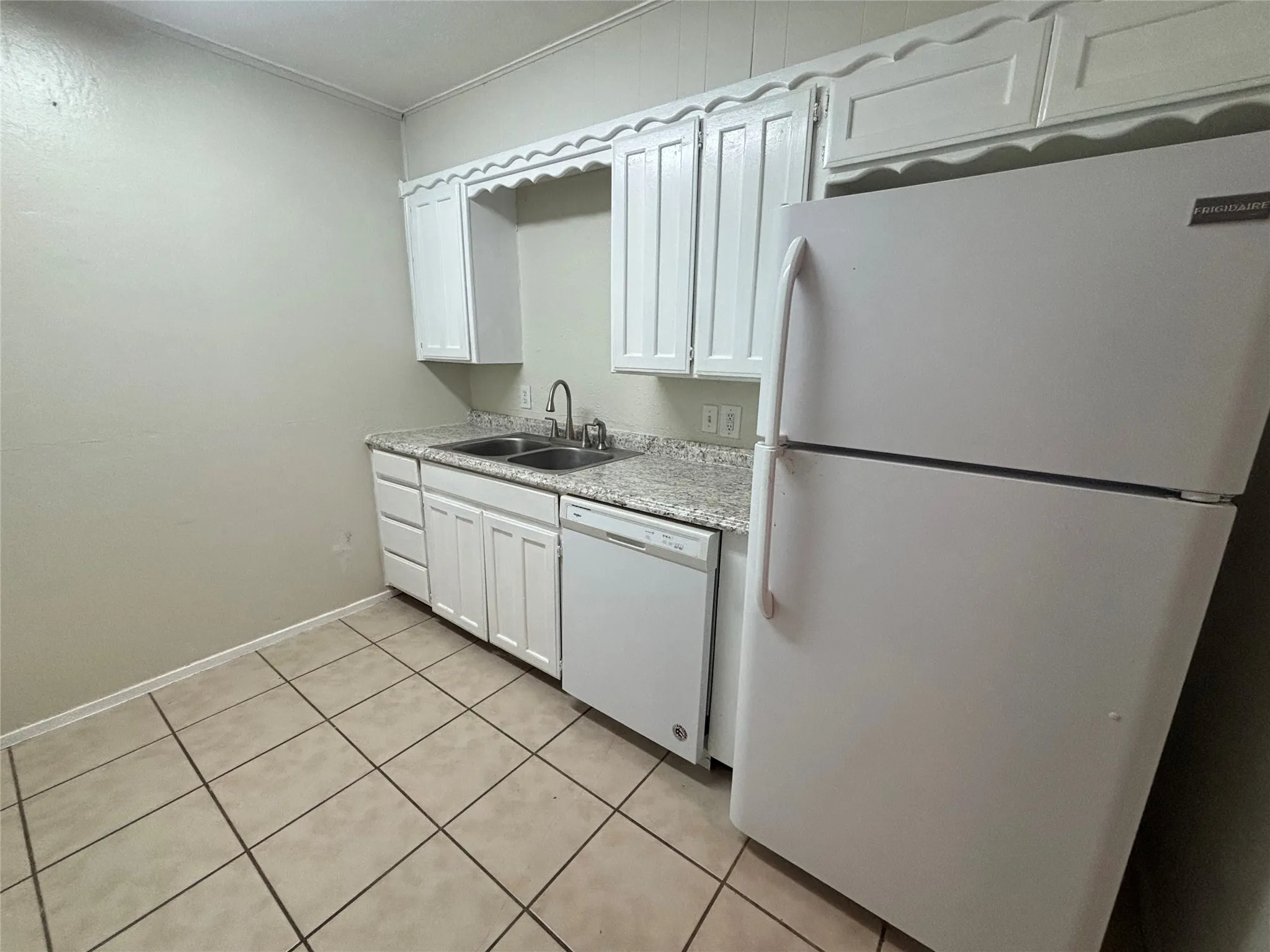 Kitchen featuring white cabinetry, light-colored countertops, a double basin sink with a gooseneck faucet, a white dishwasher, and tile flooring