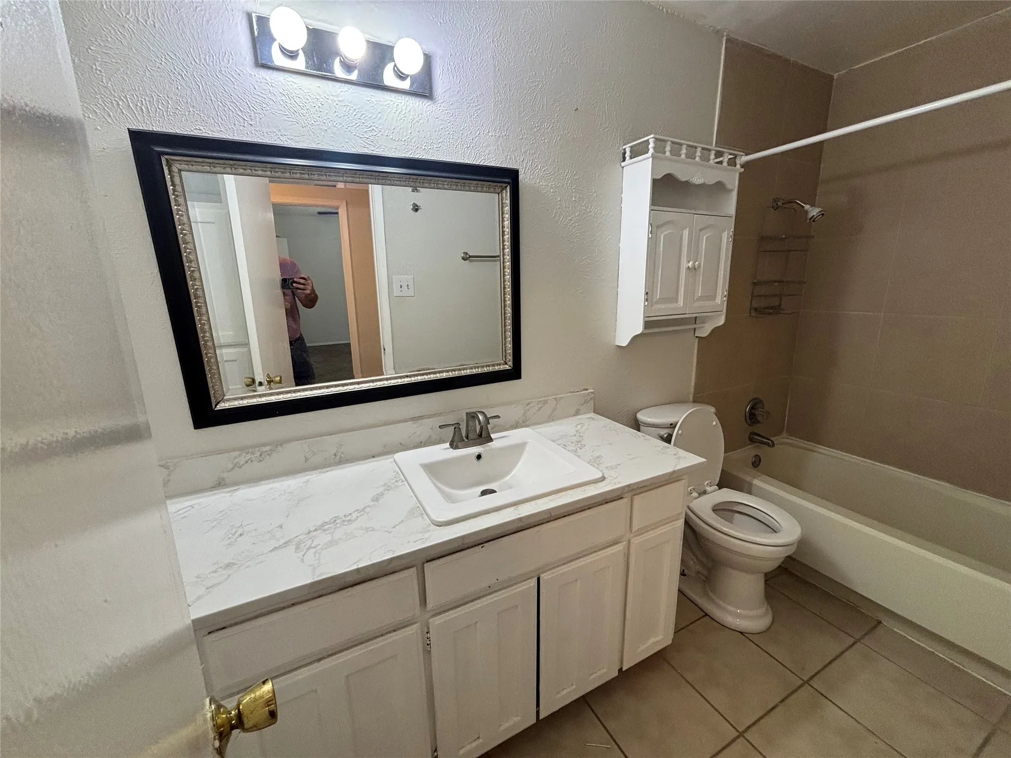 Bathroom featuring a vanity with an integrated sink, a large framed mirror, and a three-light fixture