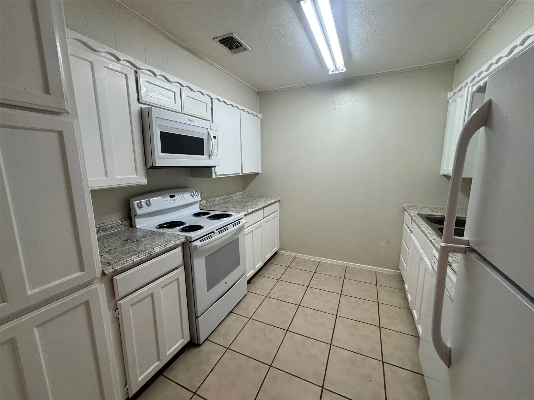 Kitchen featuring white cabinetry with decorative trim, light-toned granite-style countertops, white electric range, and an over-the-range microwave