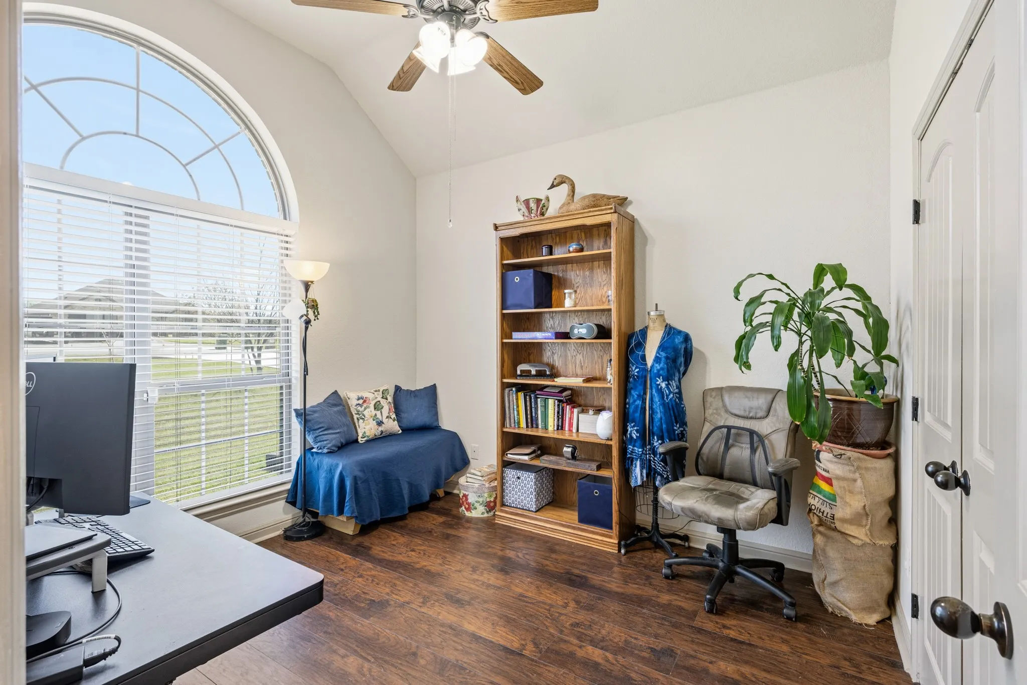 Secondary bedroom features a large window overlooking the front of the house and a ceiling fan.