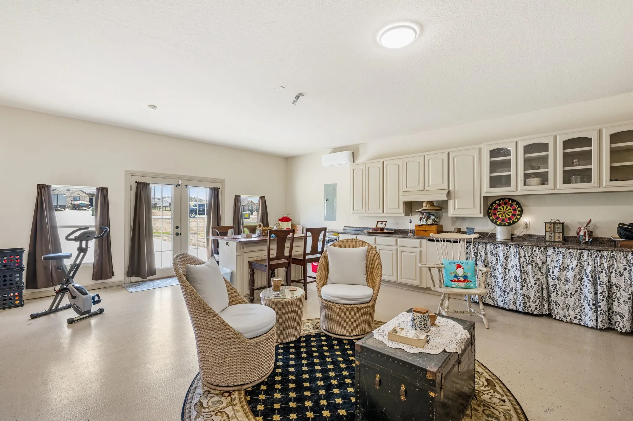Versatile recreation room with ample space for lounging, games, or hobbies, featuring built-in cabinetry and a functional kitchenette area. Bright and open with direct outdoor access, perfect for entertaining or multi-purpose use.