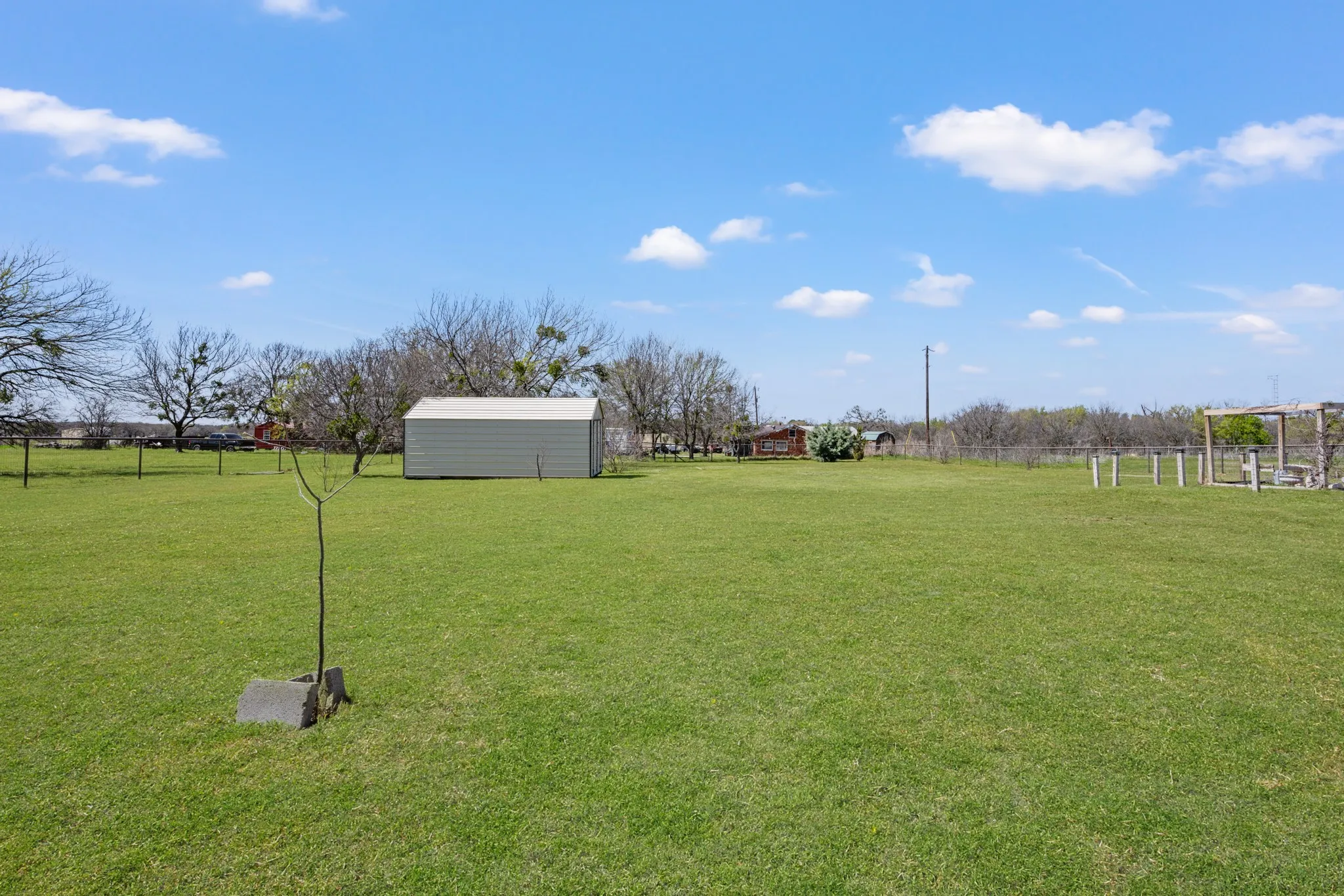 Expansive backyard with wide open green space, perfect for outdoor activities, gardening, or future additions. Includes multiple storage buildings and covered parking, offering plenty of room for equipment, hobbies, or recreational vehicles.