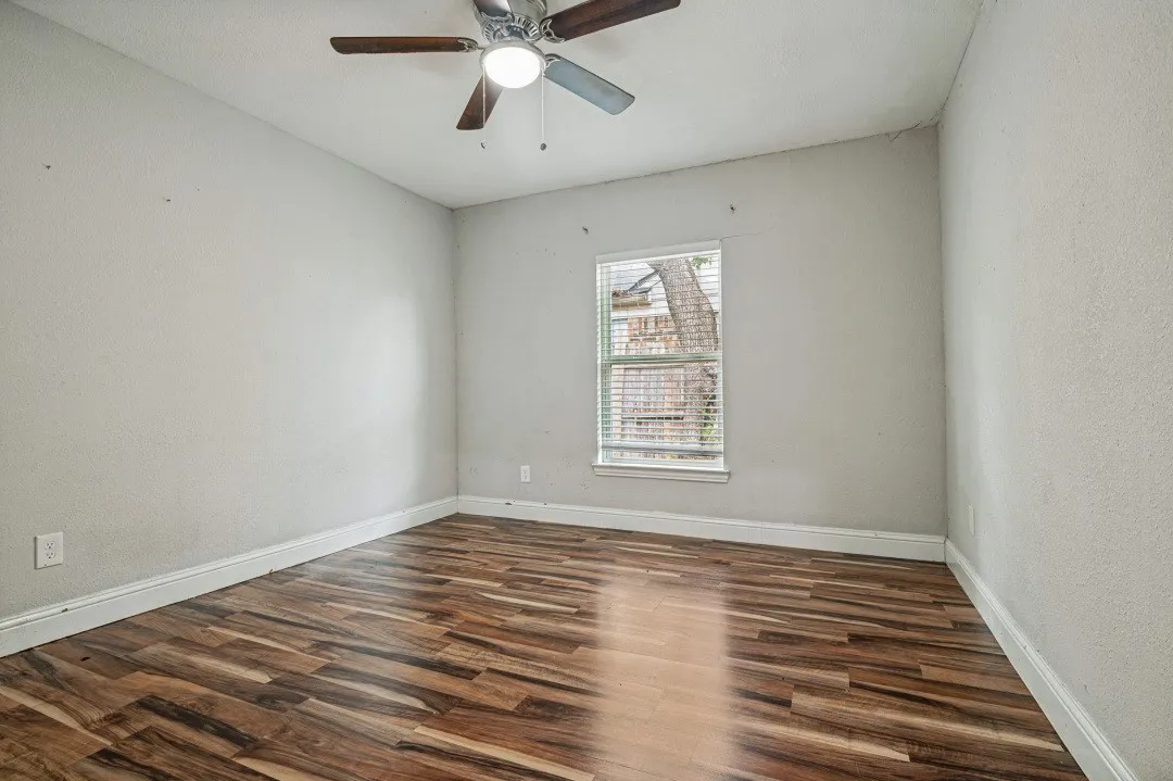 Room featuring wood-finish flooring, white baseboards, a window with horizontal blinds, and a ceiling fan with light fixture