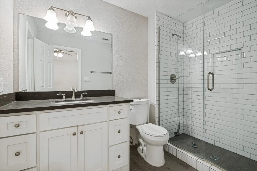 Bathroom featuring a white vanity with dark countertop, undermount sink, and brushed nickel fixtures