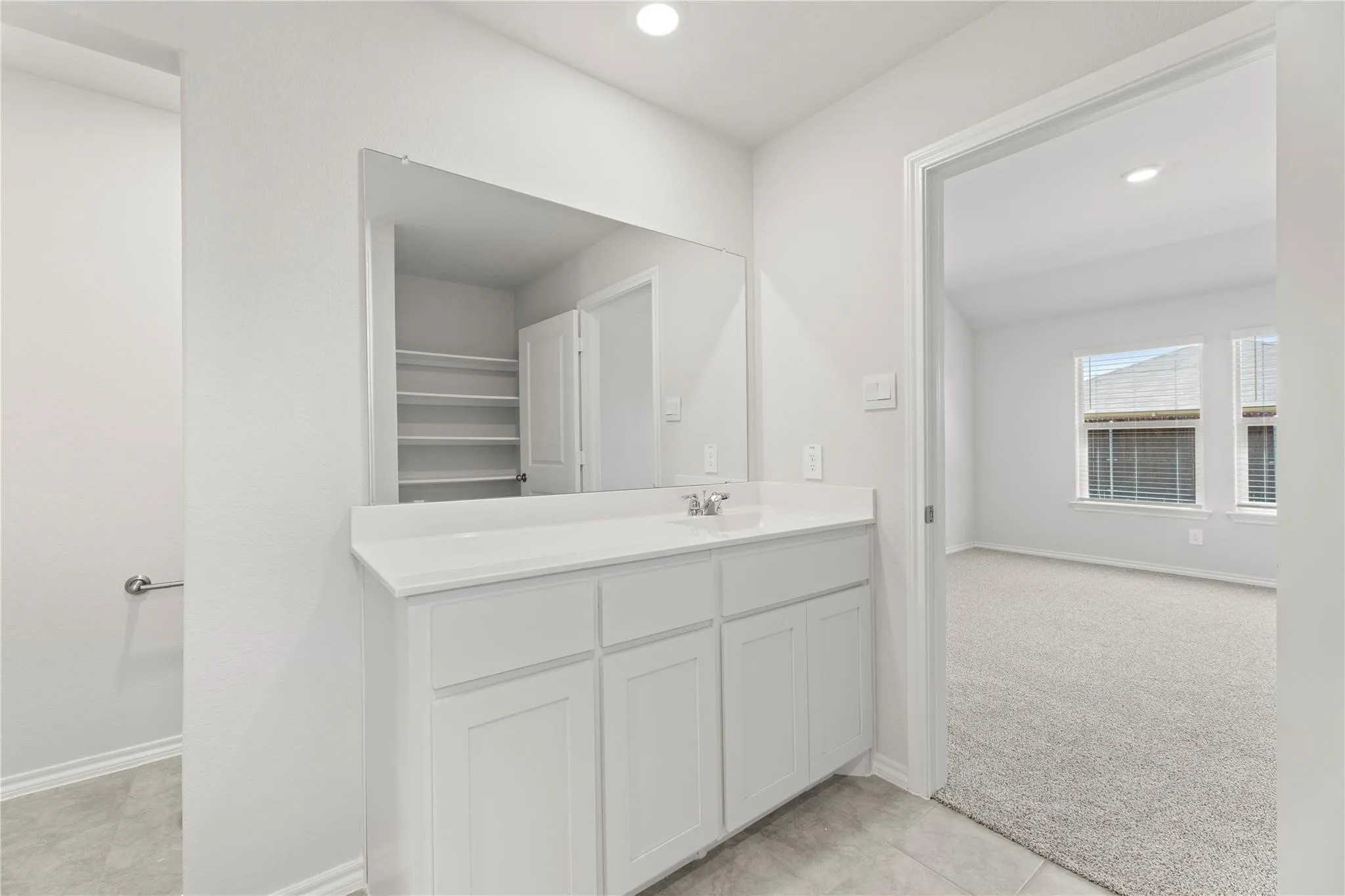 Vanity area featuring a built-in sink with a single-handle faucet, white cabinetry, and a countertop with integrated backsplash