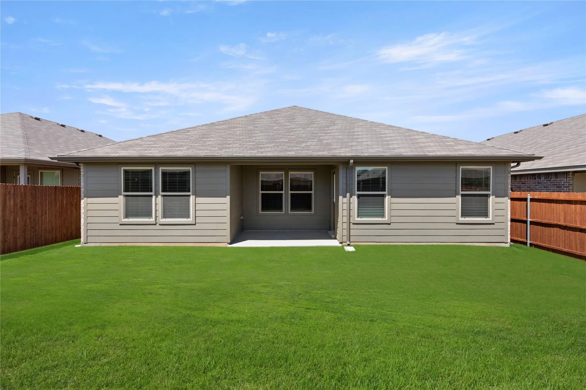 Rear exterior featuring a covered concrete patio, grey horizontal siding, and a shingle roof