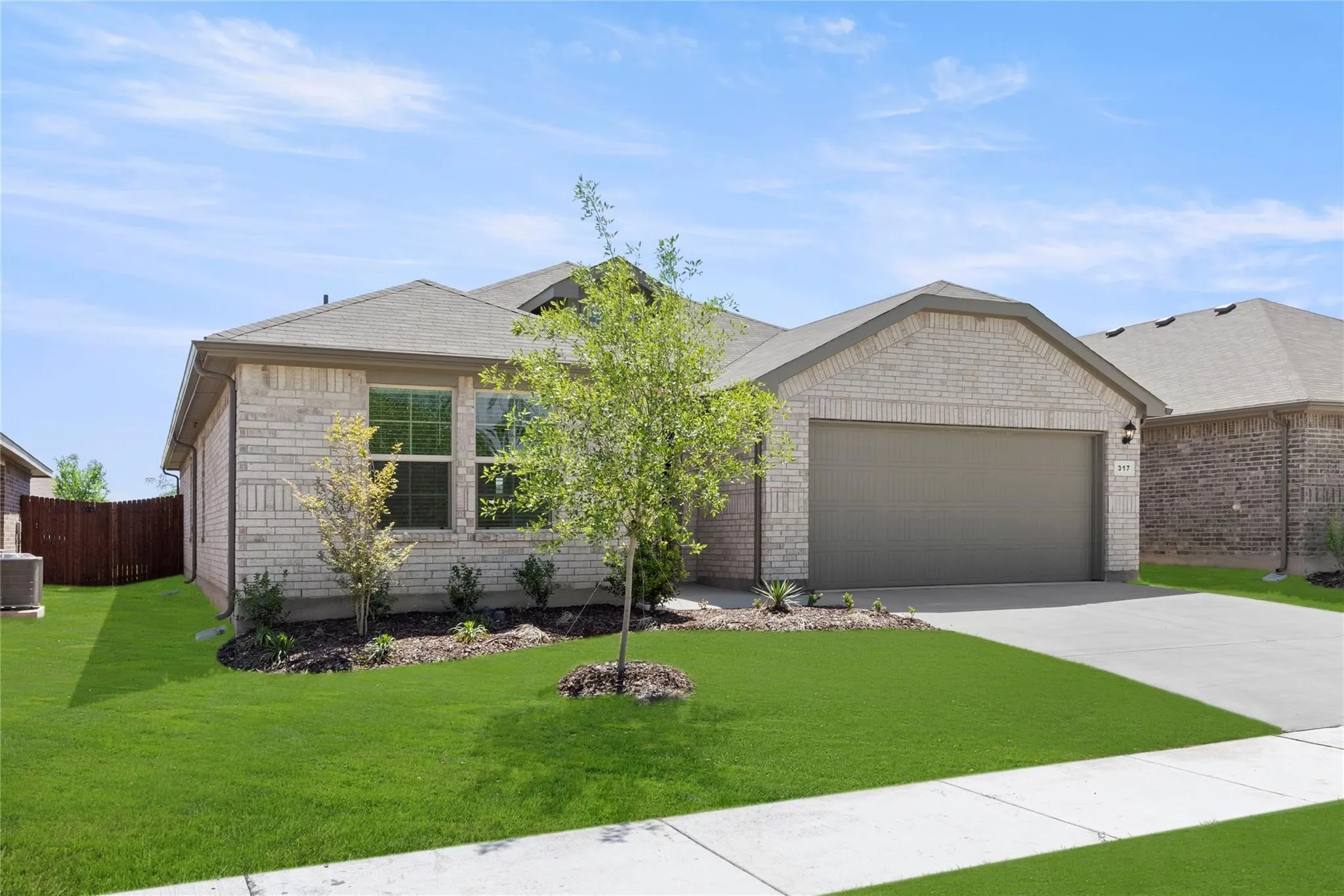 Single-story residence featuring light-colored brick exterior, attached garage, and a lush green lawn