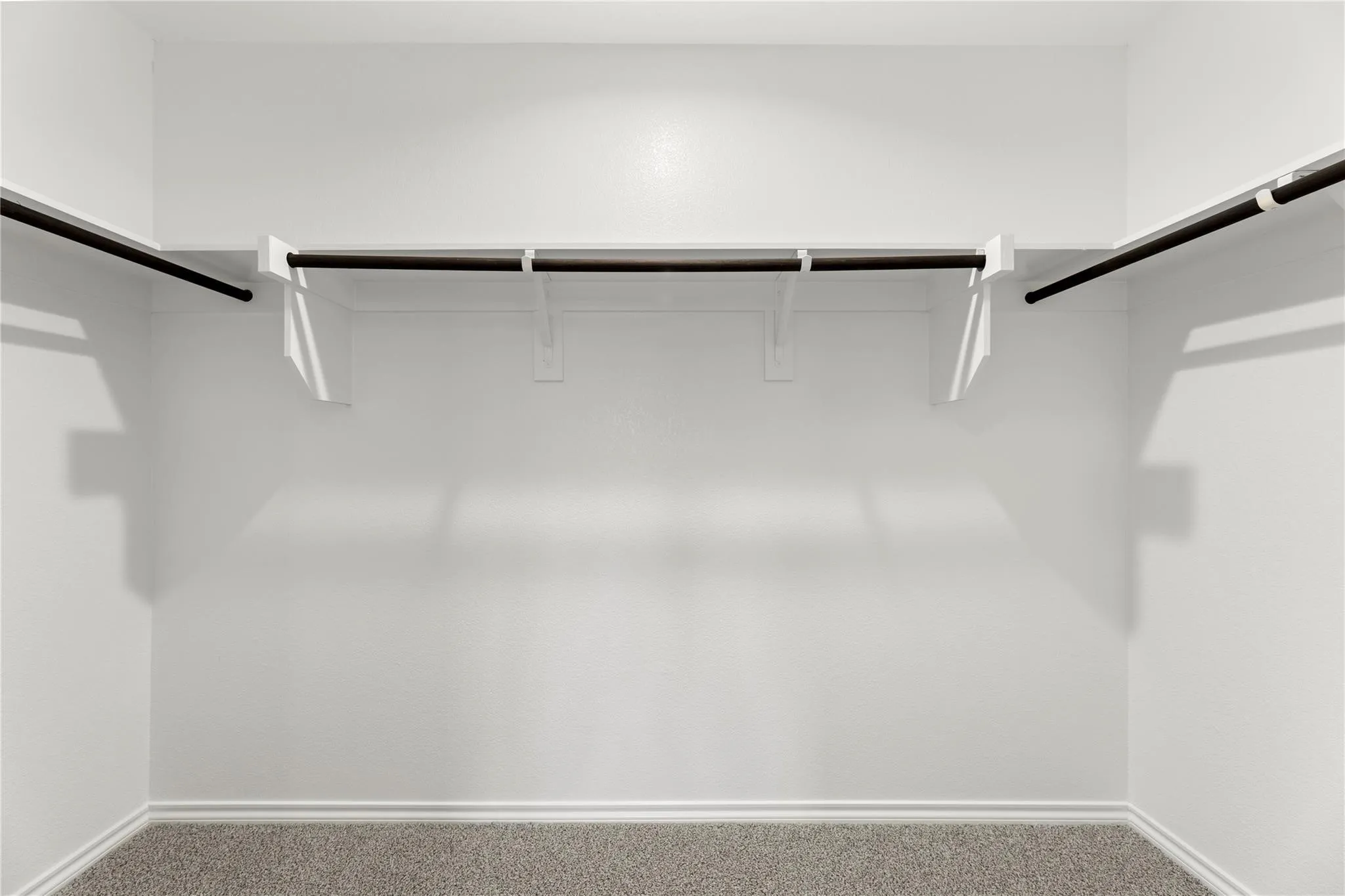 Interior closet with white walls, white trim, and gray carpet flooring