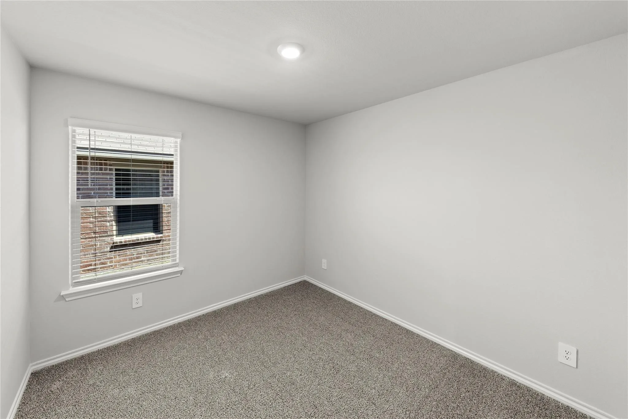 Carpeted interior room with white baseboards and walls