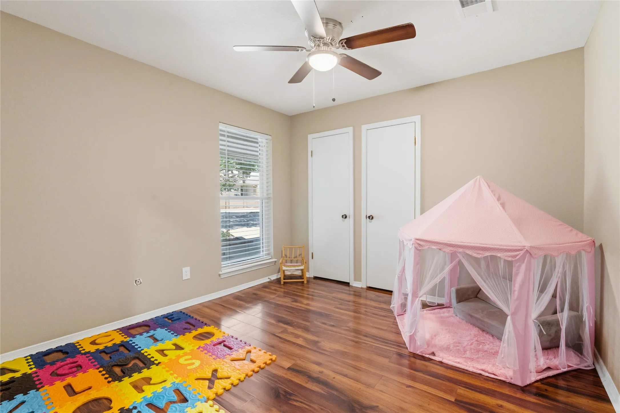 Room featuring wood-finish flooring, a ceiling fan with integrated lighting, and neutral wall tones