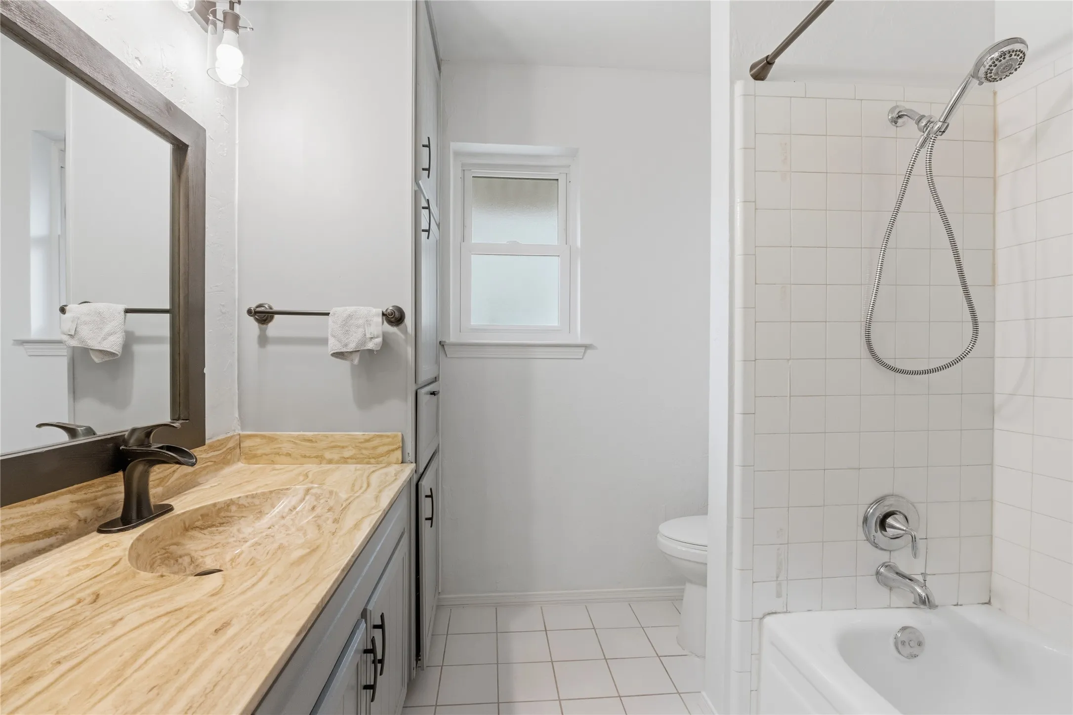 Bathroom featuring a built-in vanity with a stone countertop and integrated basin, dark bronze faucet, framed mirror, and overhead lighting
