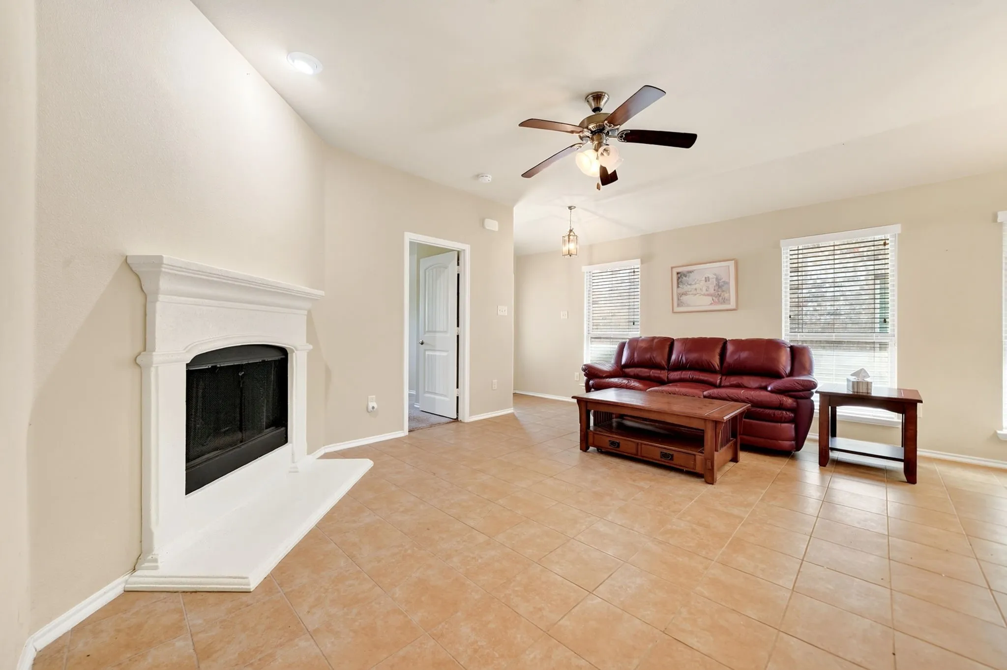 Living area featuring a classic fireplace with a white mantel and hearth, ceramic tile flooring, a ceiling fan with integrated lighting, and recessed ceiling lights