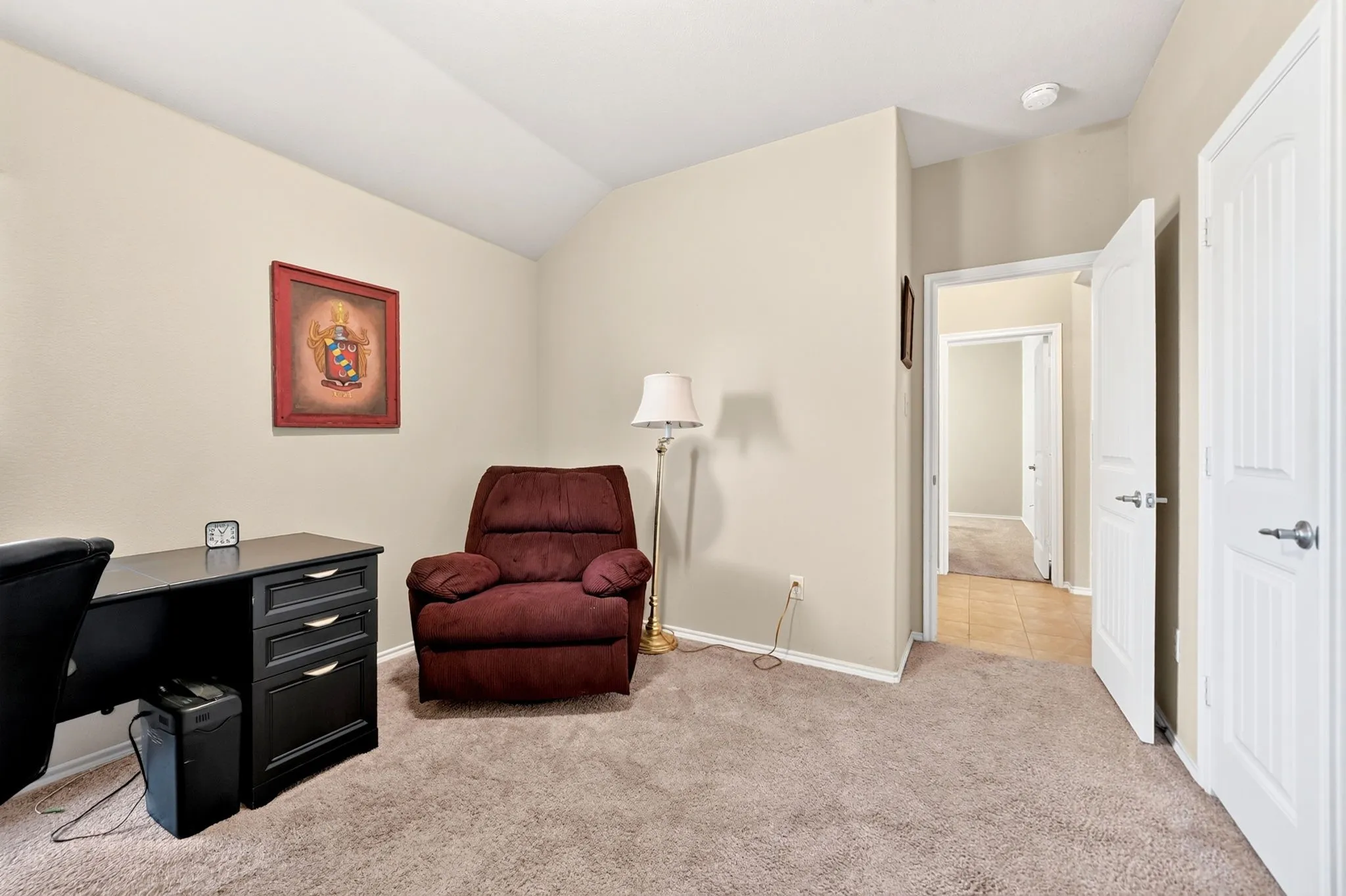 Carpeted room featuring a vaulted ceiling and neutral wall tones