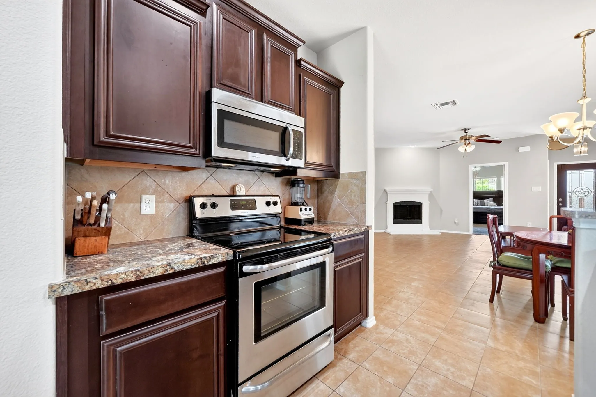 Kitchen featuring dark wood cabinetry, stainless steel appliances including a microwave and range, and a tiled backsplash