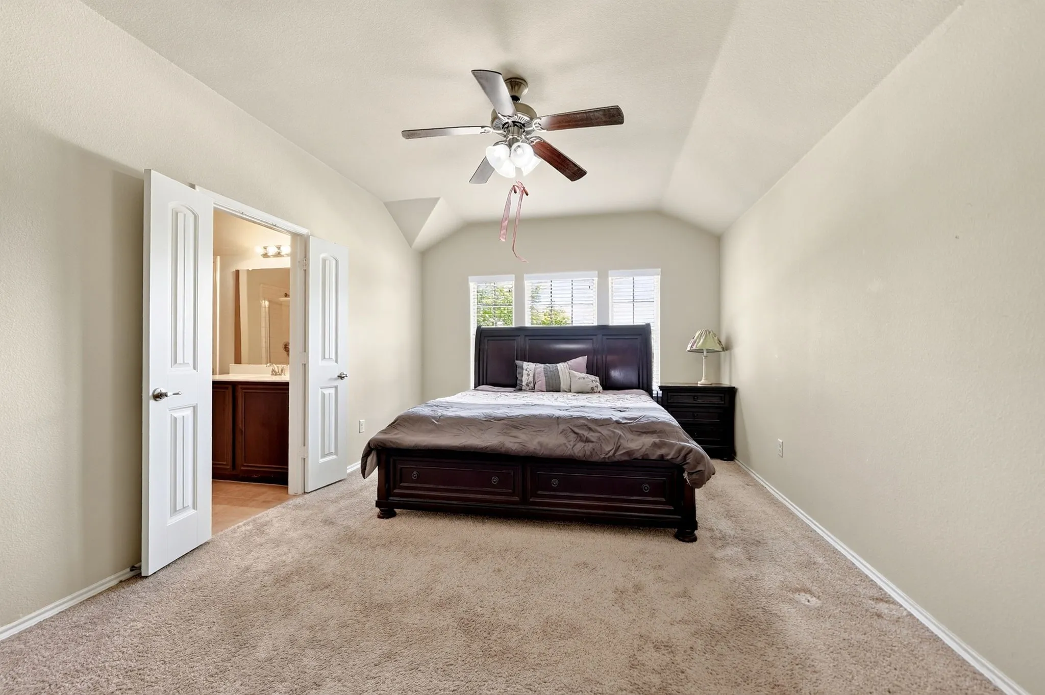 Vaulted ceiling bedroom with carpet flooring and a ceiling fan with light fixture