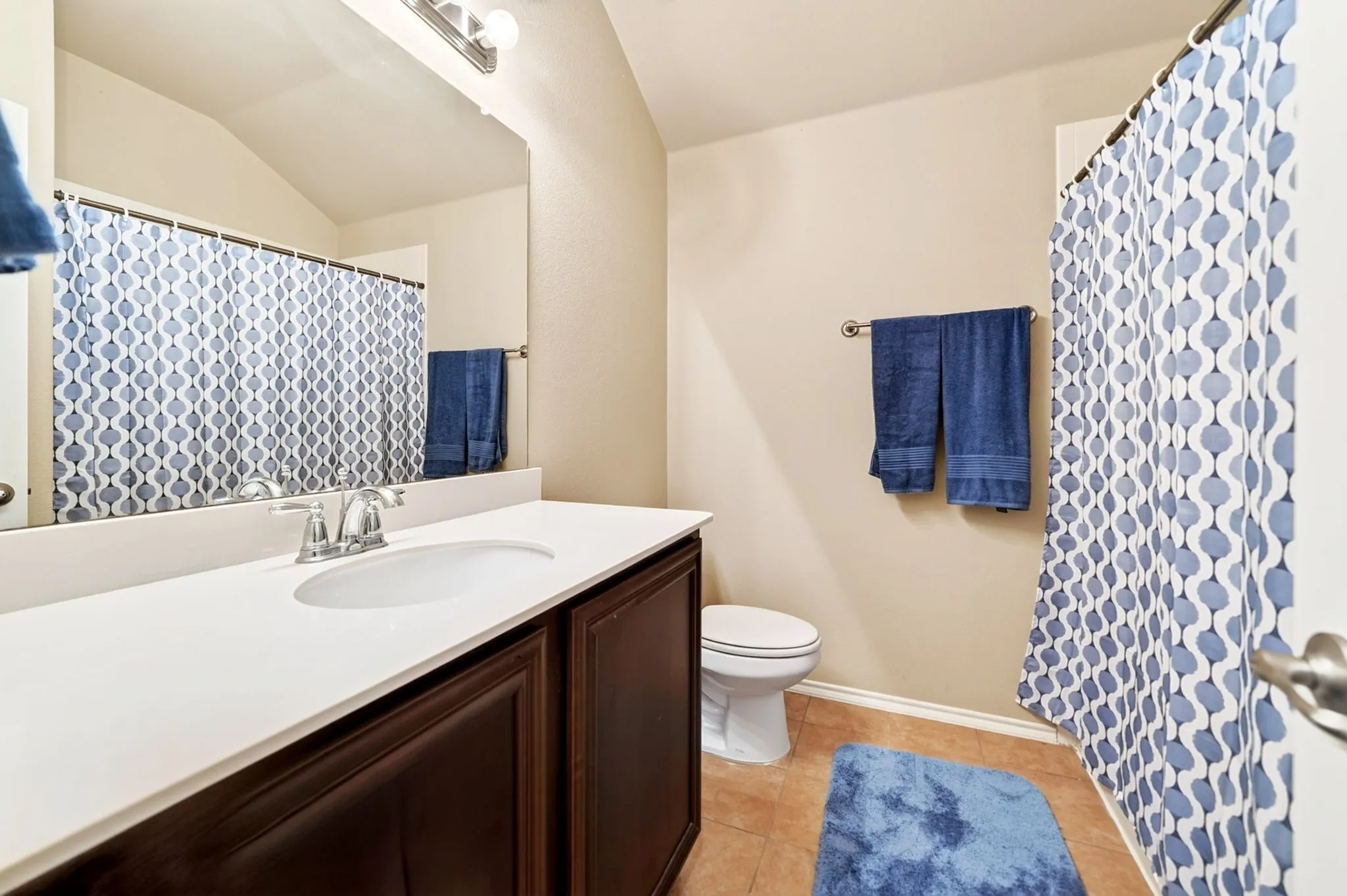 Spacious bathroom featuring a single vanity with a white countertop and dark wood cabinetry
