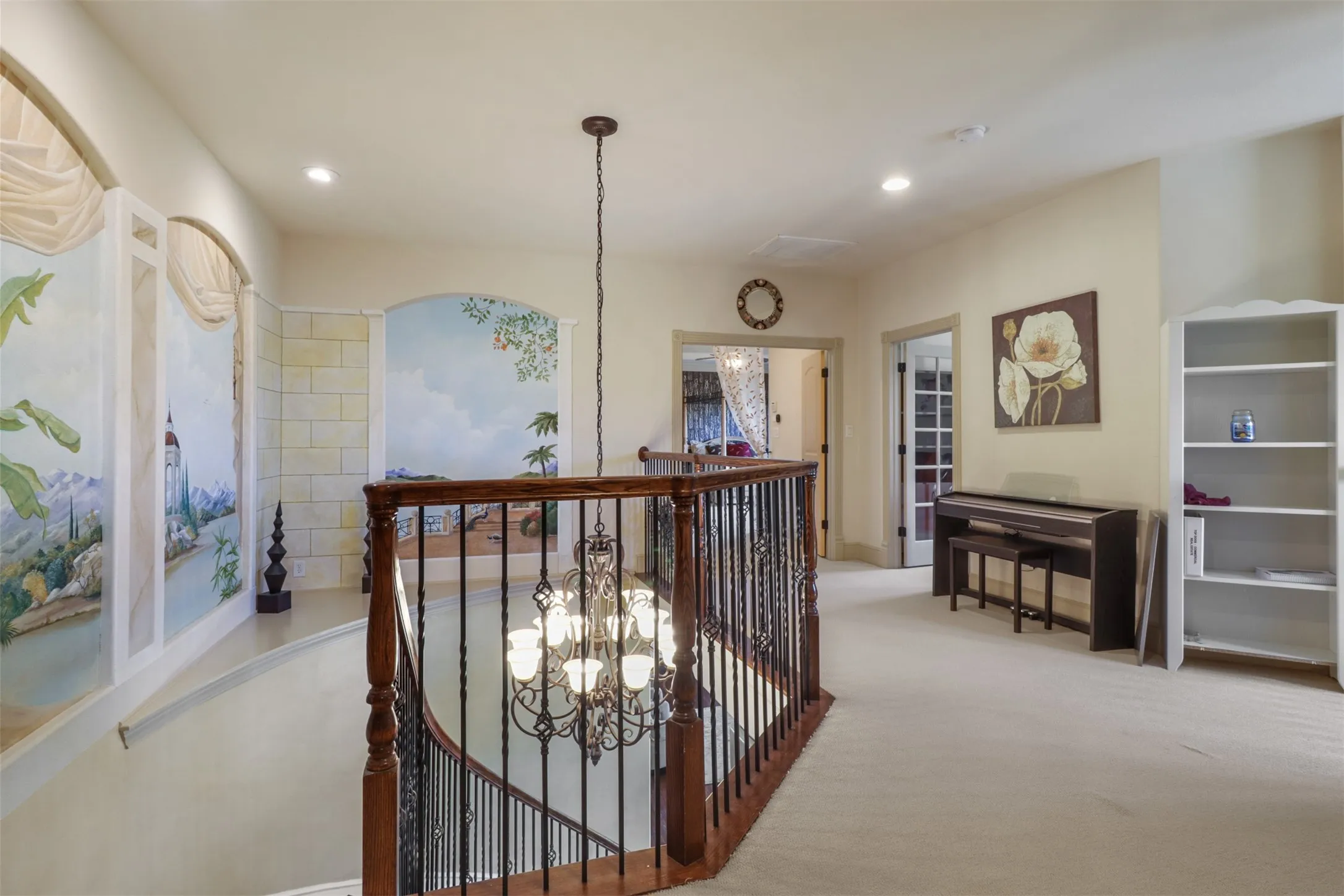 Upper-level landing featuring a curved staircase with dark wood handrails and wrought iron balusters