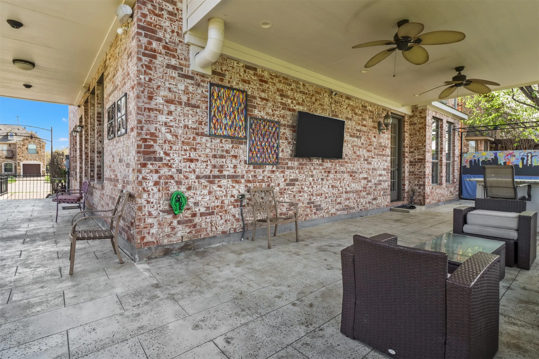 Covered outdoor patio with a brick wall, recessed lighting, and dual ceiling fans