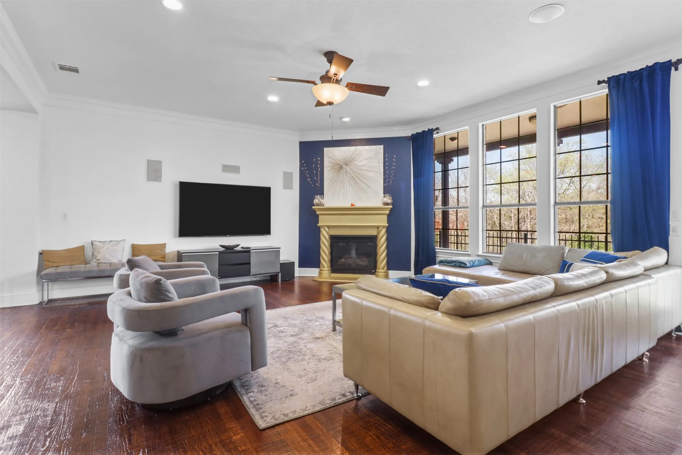 Hardwood flooring complements a fireplace with a decorative mantel and a dark blue accent wall