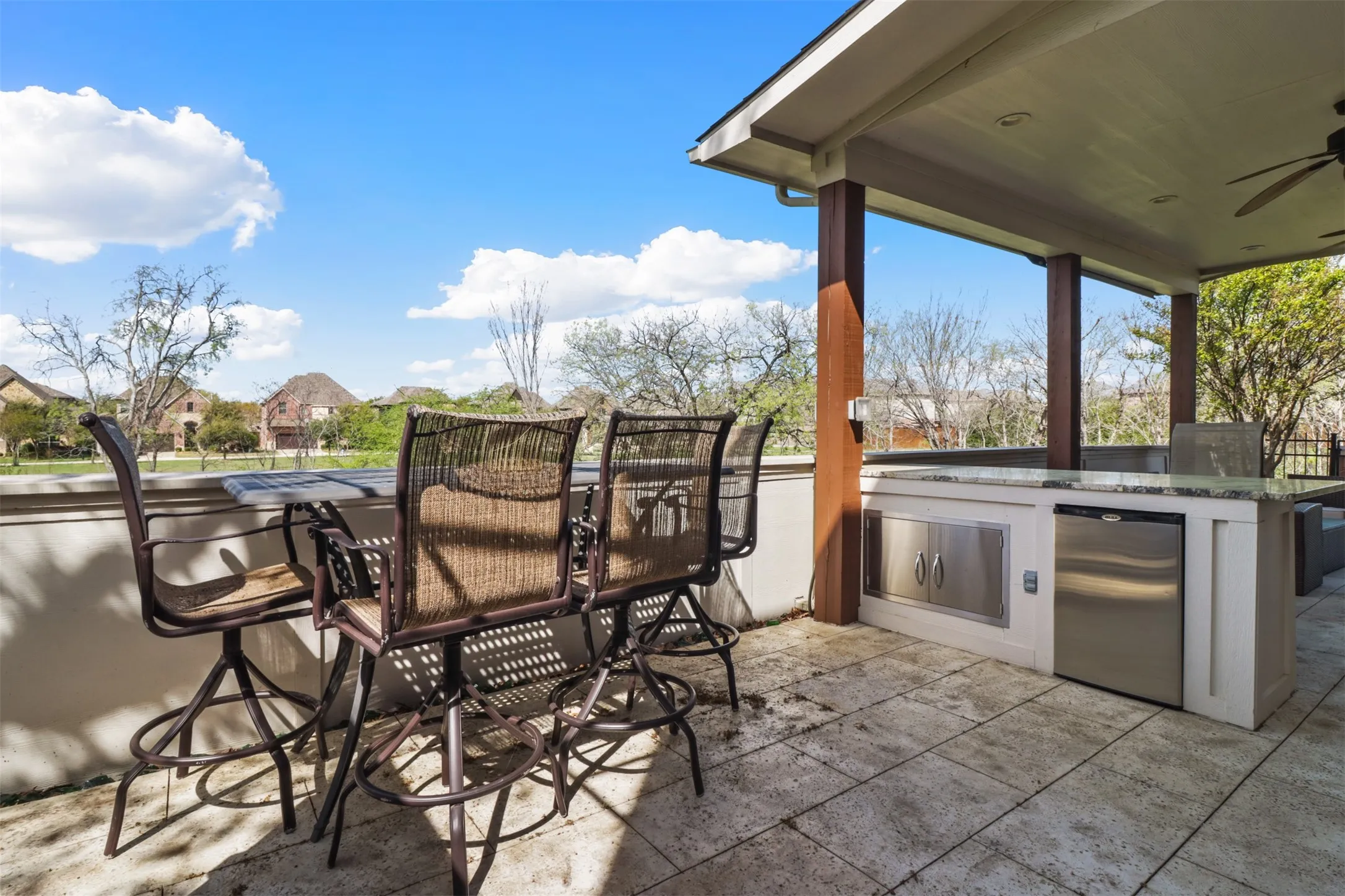 Covered outdoor patio featuring a built-in outdoor kitchen with stainless steel appliances, a stone-finish countertop, recessed lighting, and a ceiling fan