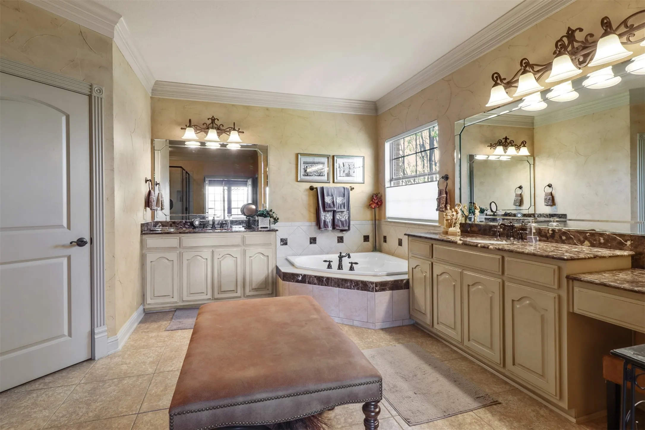 Bathroom featuring a corner built-in tub, dual vanities with stone countertops, and tile flooring