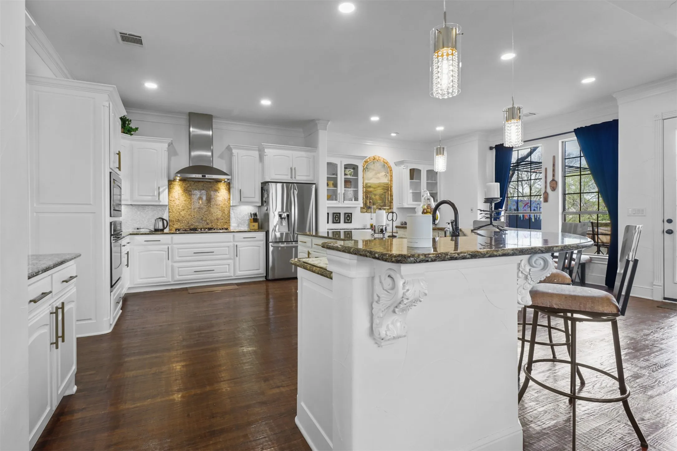 Spacious kitchen featuring white cabinetry, stainless steel appliances, granite countertops, a decorative tile backsplash, and dark wood-finish flooring