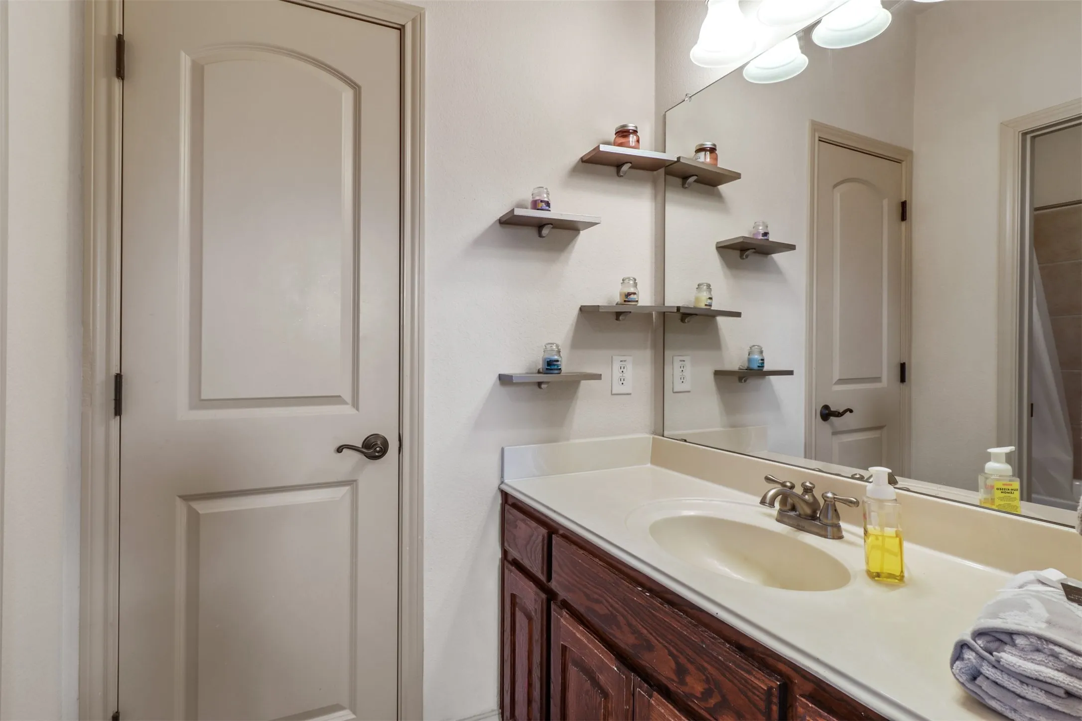 Single vanity with an integrated sink, a rectangular mirror, and a three-bulb light fixture