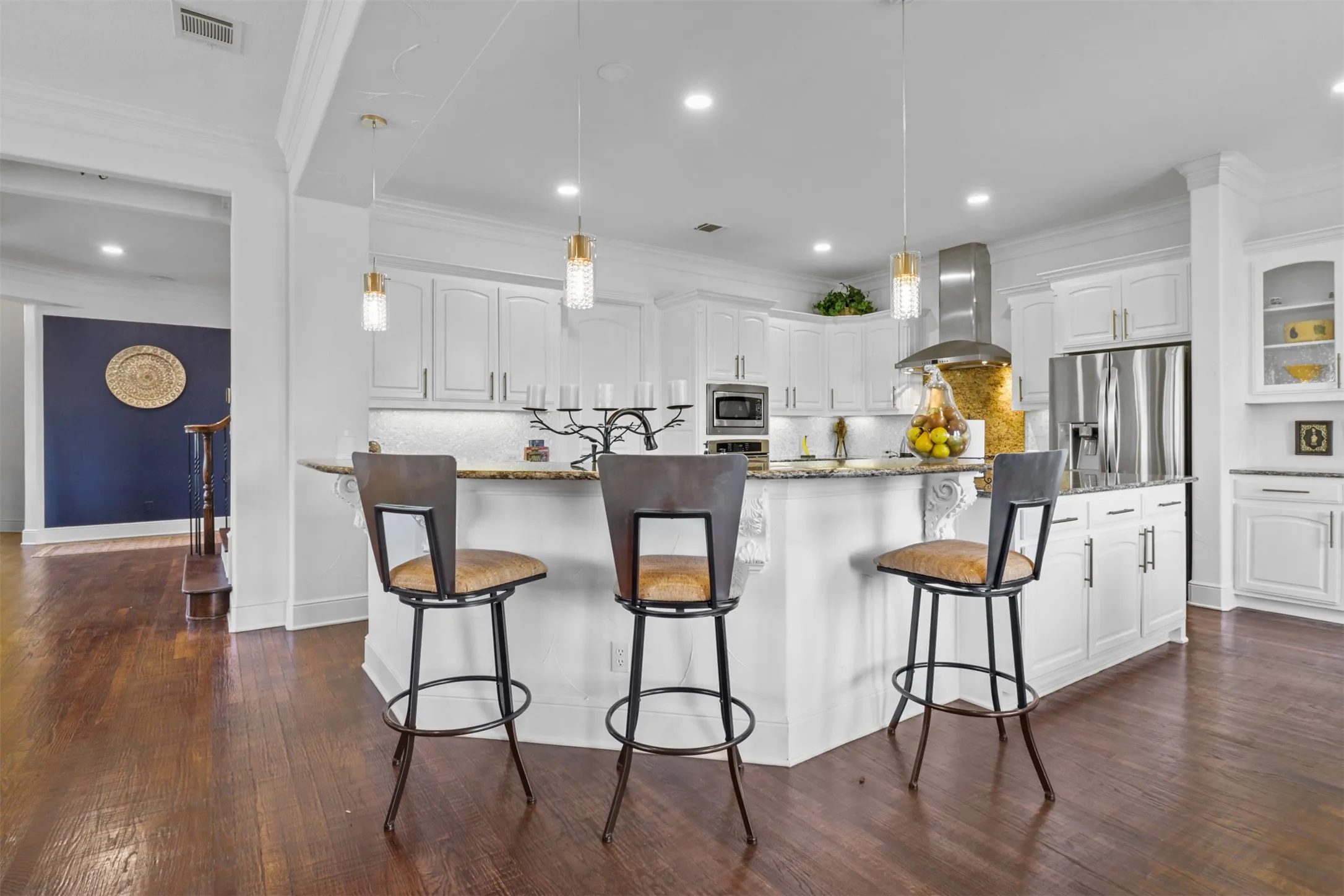 Gourmet kitchen featuring white cabinetry, stainless steel appliances, a multi-level island with seating, and a mosaic tile backsplash