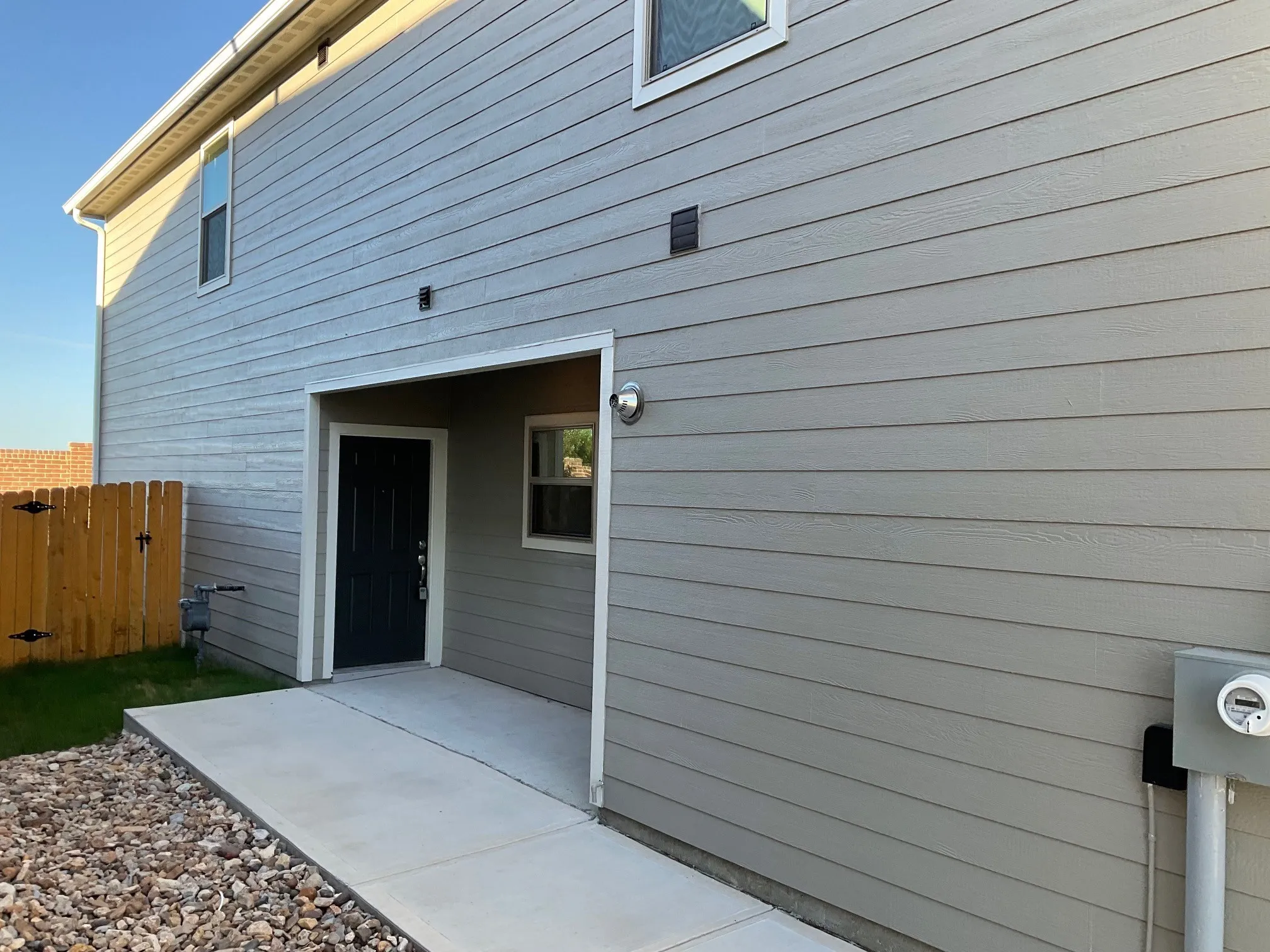 Two-story building featuring tan horizontal siding and vertical paneling on the upper level