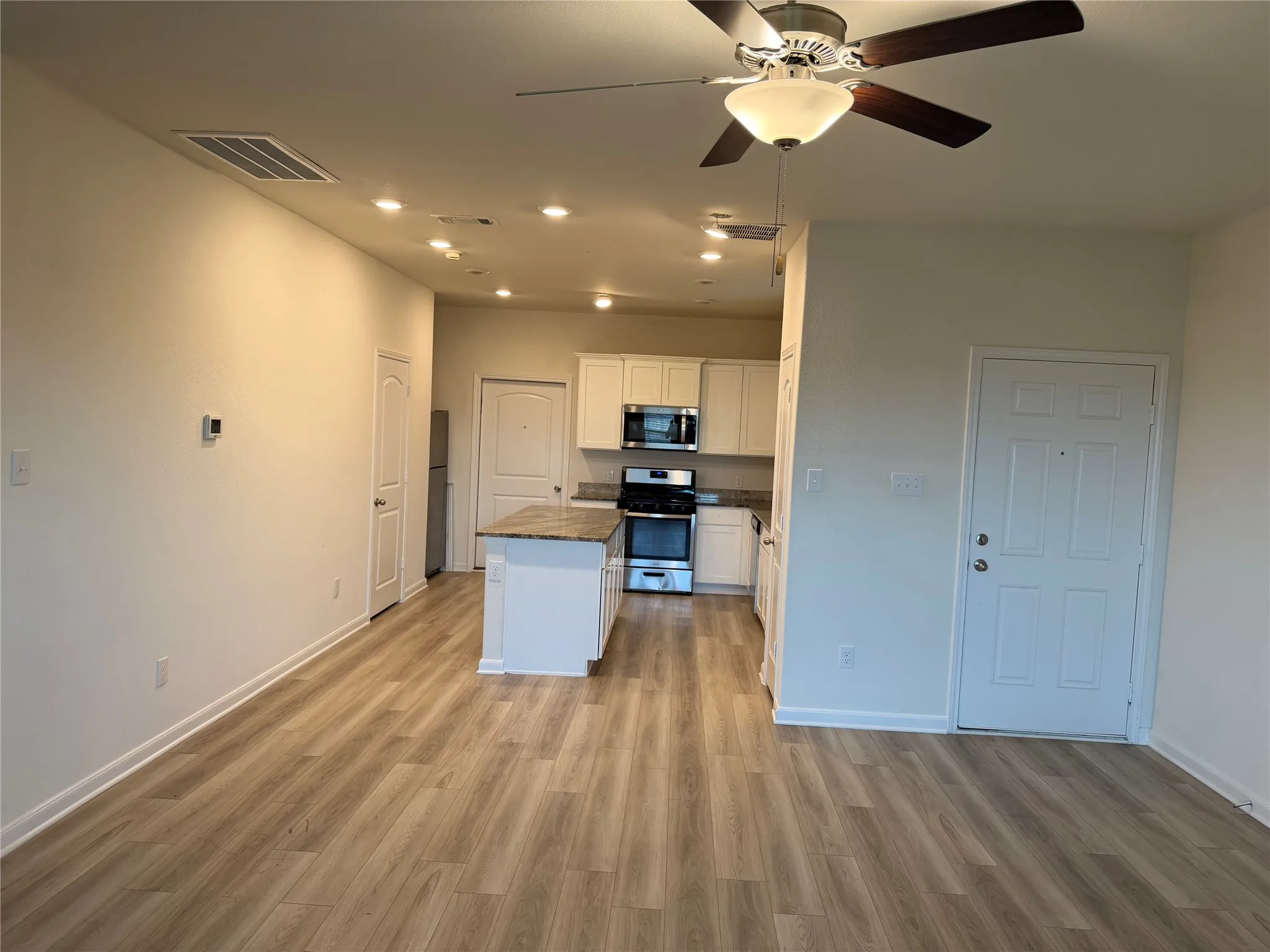 Open-concept living area with wood-finish flooring, recessed lighting, and a ceiling fan