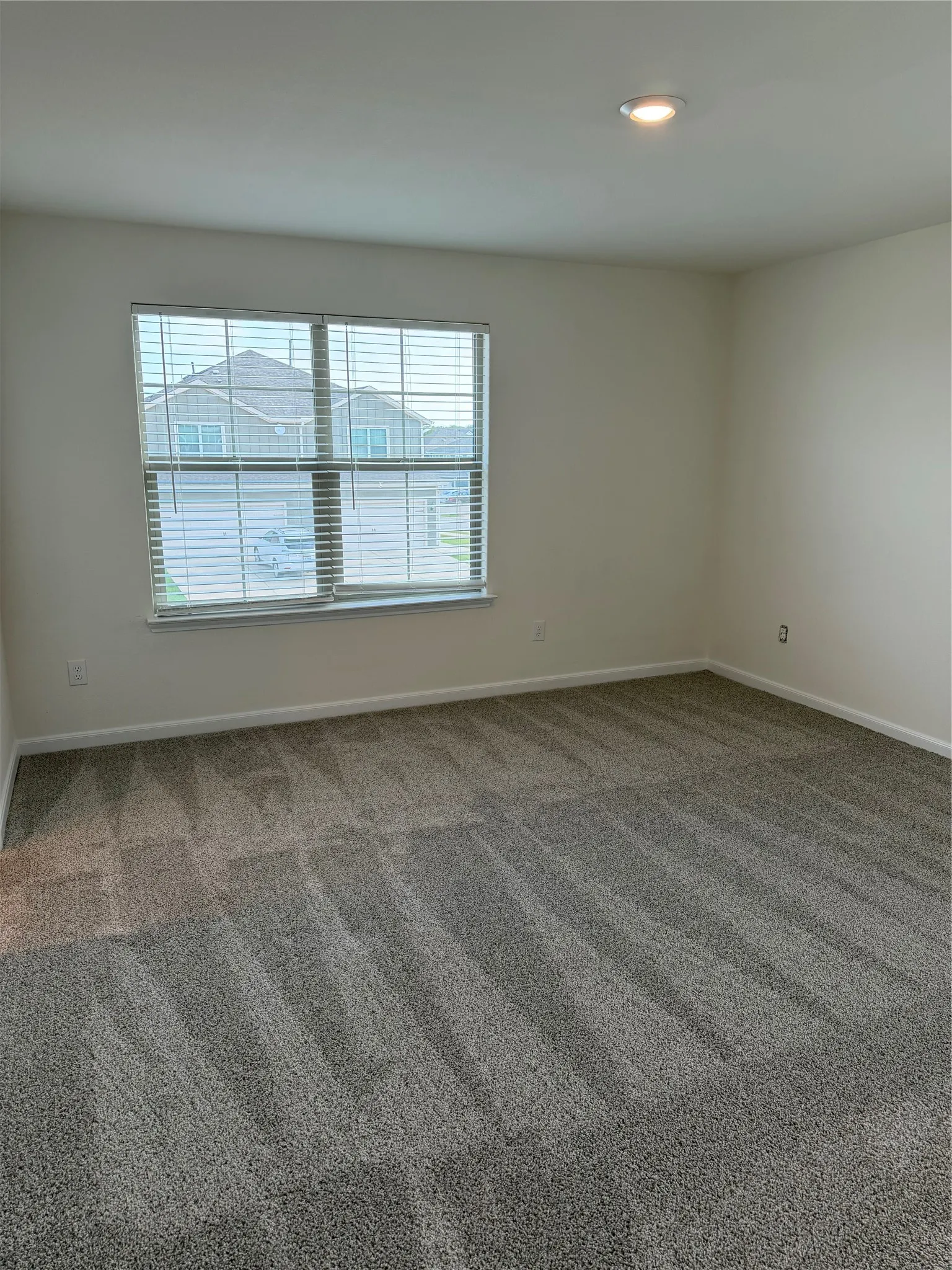 Spacious room featuring neutral-toned walls, recessed lighting, and soft carpet flooring