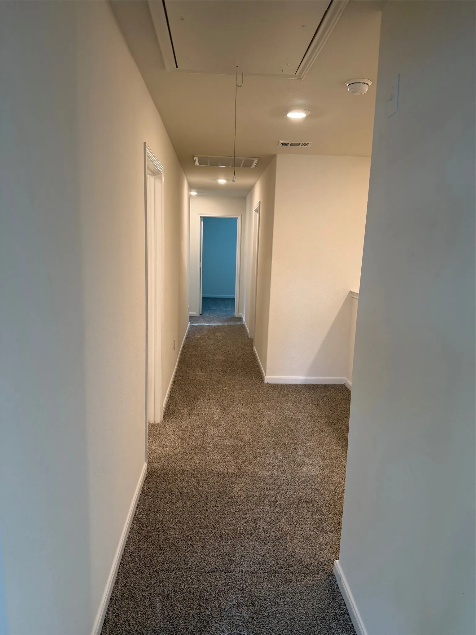 Carpeted hallway featuring recessed lighting, light neutral wall paint, white trim, and doors with white frames