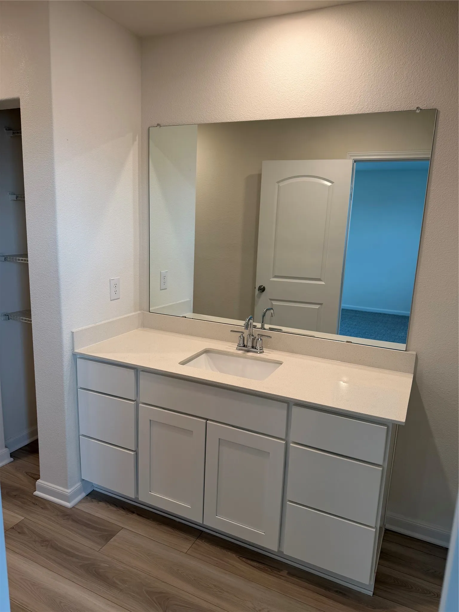 Spacious vanity with a light countertop, integrated sink, and white cabinetry featuring both drawers and under-sink storage