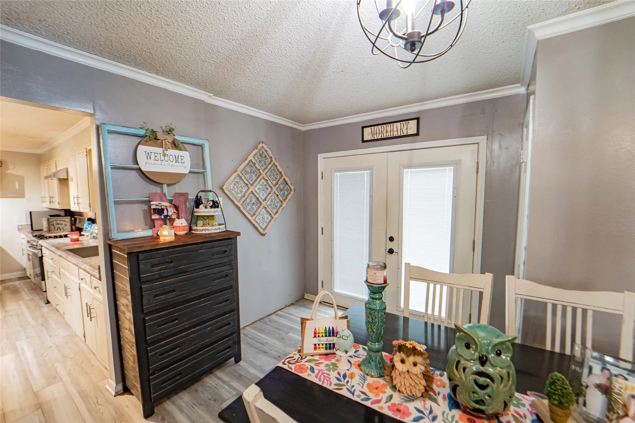 Dining area featuring light grey walls, white crown molding, and wood-finish flooring