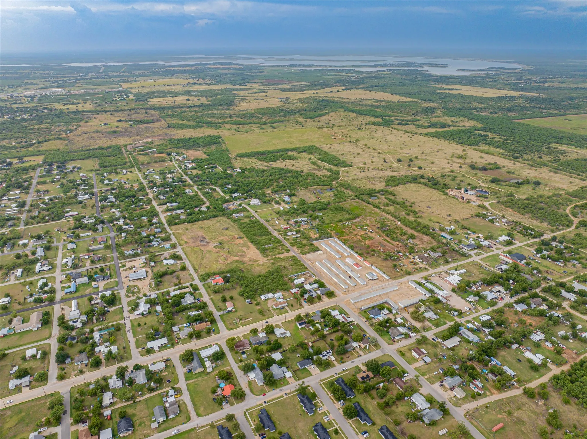 Aerial perspective showcasing a residential community surrounded by expansive green spaces and distant bodies of water