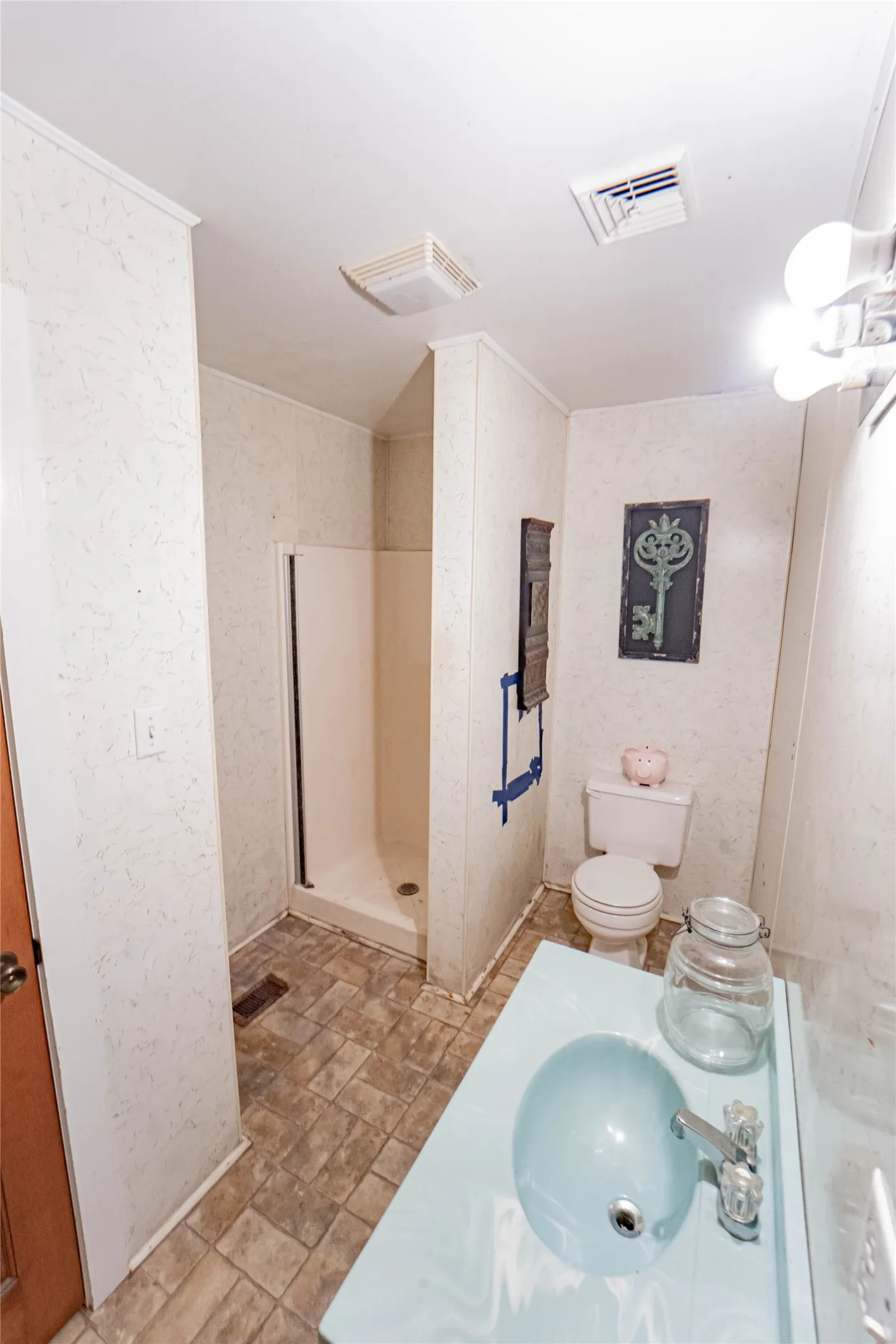 Bathroom featuring a walk-in shower with white enclosure, a toilet, and a vanity with a light blue basin
