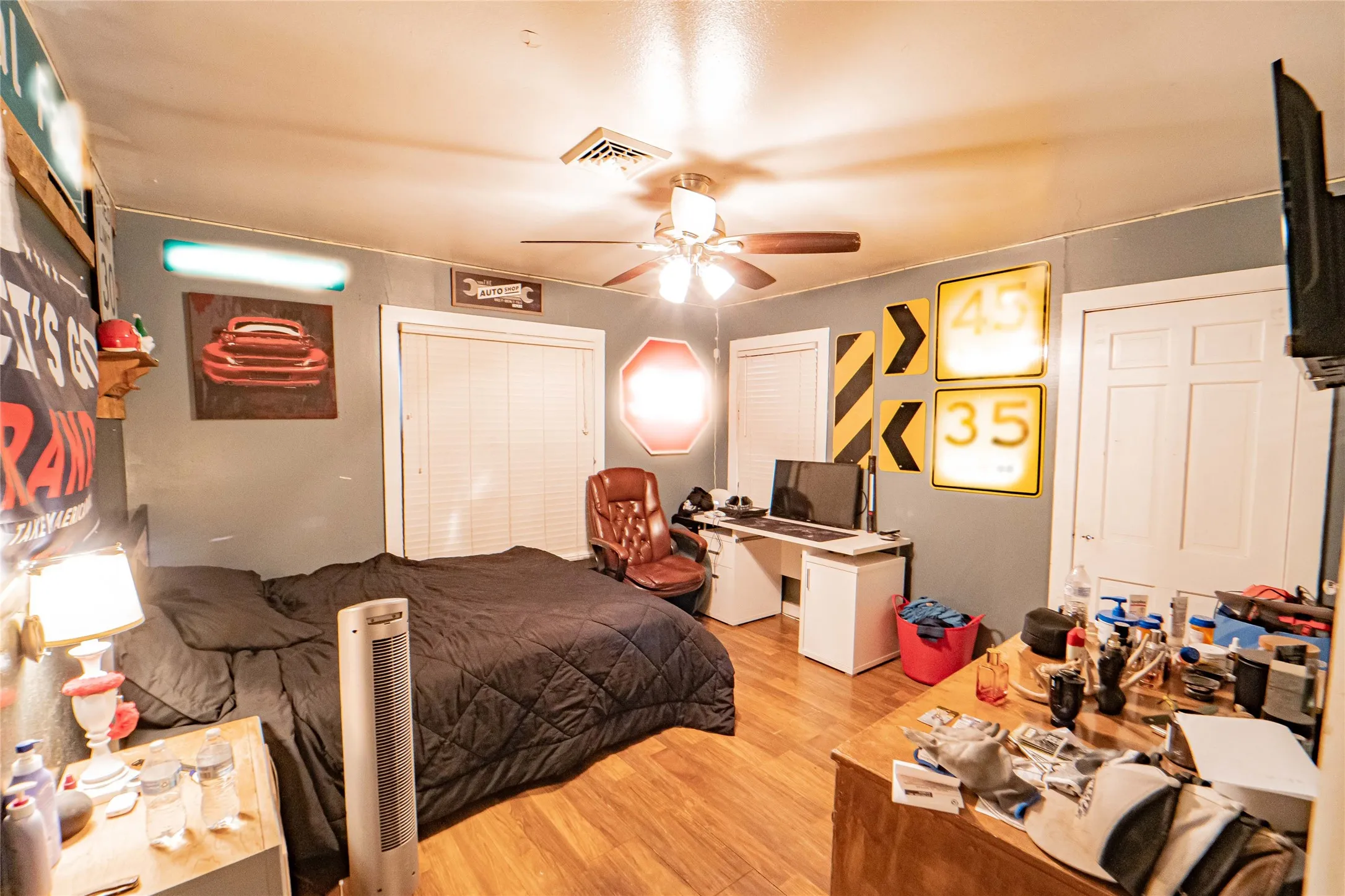 Bedroom featuring wood-finish flooring, a ceiling fan with light fixture, and light gray wall paint