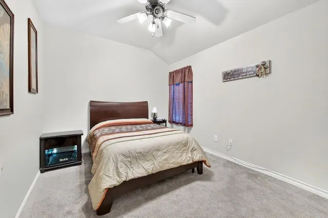 Carpeted room featuring a vaulted ceiling and a ceiling fan with light fixture