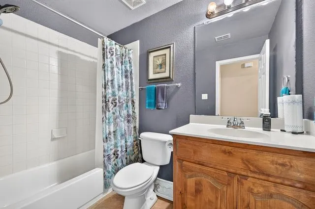 Bathroom featuring a white subway tile shower surround, a built-in bathtub, a wood-finish vanity with a white countertop, and a wall-mounted mirror