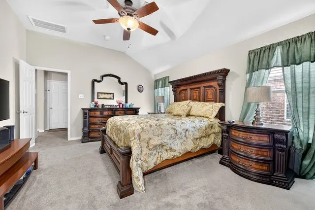 Bedroom featuring a vaulted ceiling with a ceiling fan, carpet flooring, and two windows with blinds