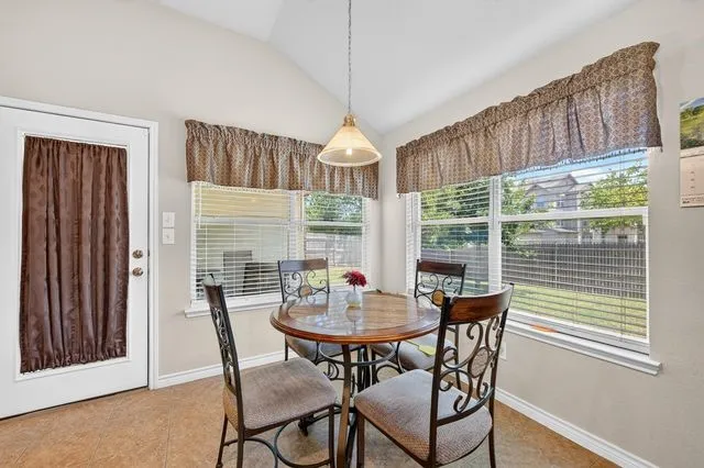 Vaulted ceiling dining area featuring ample natural light, a pendant light fixture, and a white exterior door