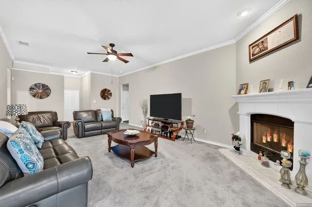 Living area featuring a fireplace with a mantel, recessed lighting, and crown molding