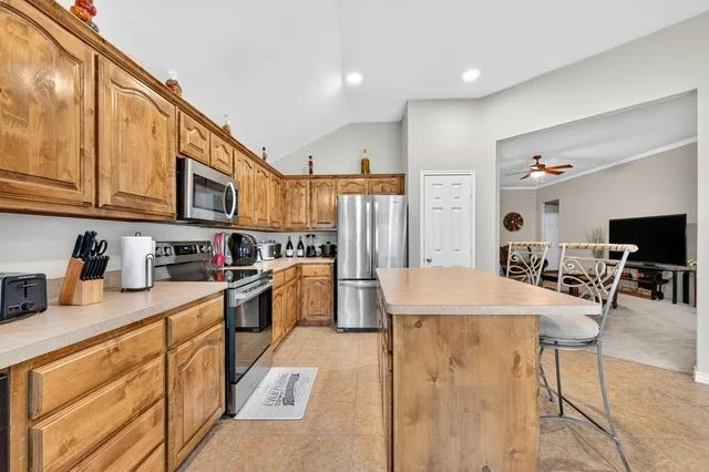 Kitchen featuring wood cabinetry, stainless steel appliances, and a central island with bar seating