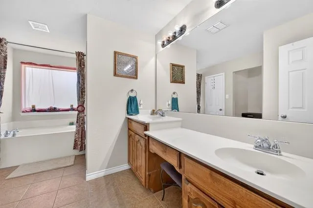 Dual vanity with integrated sinks and chrome fixtures, ample counter space, built-in cabinetry, and a full-width mirror