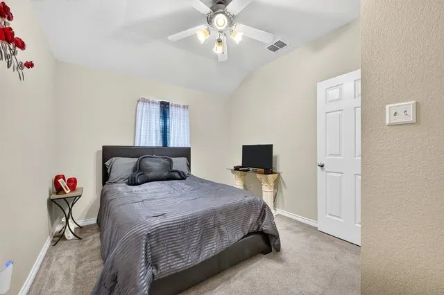 Bedroom featuring plush carpeting, a vaulted ceiling, and a ceiling fan with integrated lighting