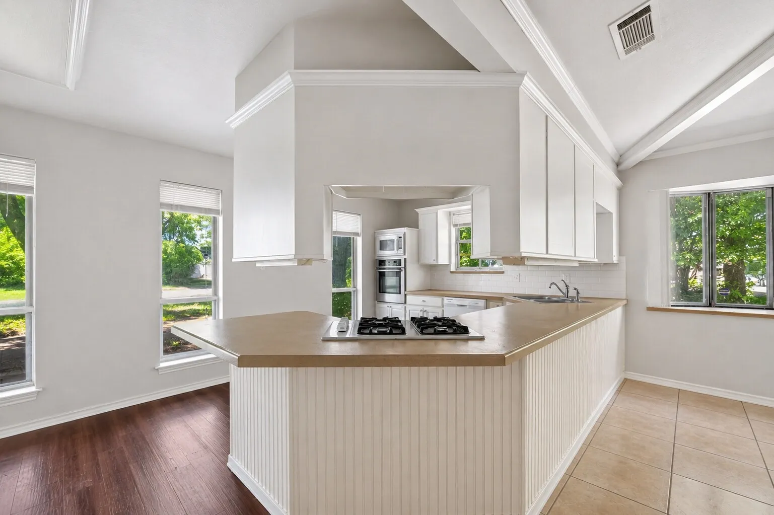 Kitchen featuring an extended peninsula with beadboard paneling, light-toned countertops, and a built-in gas cooktop